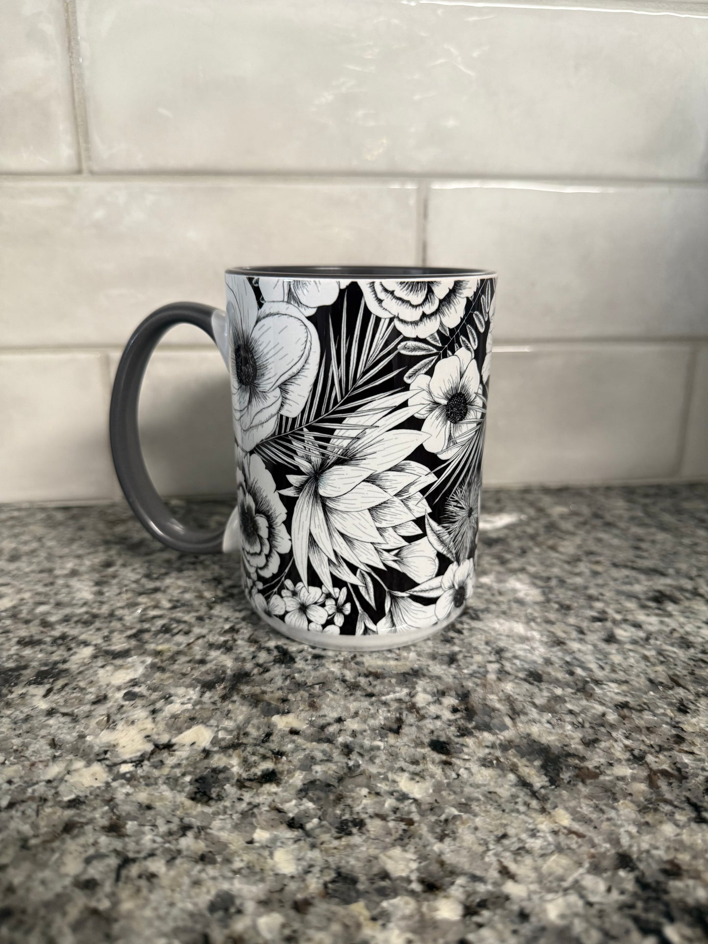 Beautiful 15 oz coffee mug with black and white botanical flower. Mug has a gray interior and gray handle.