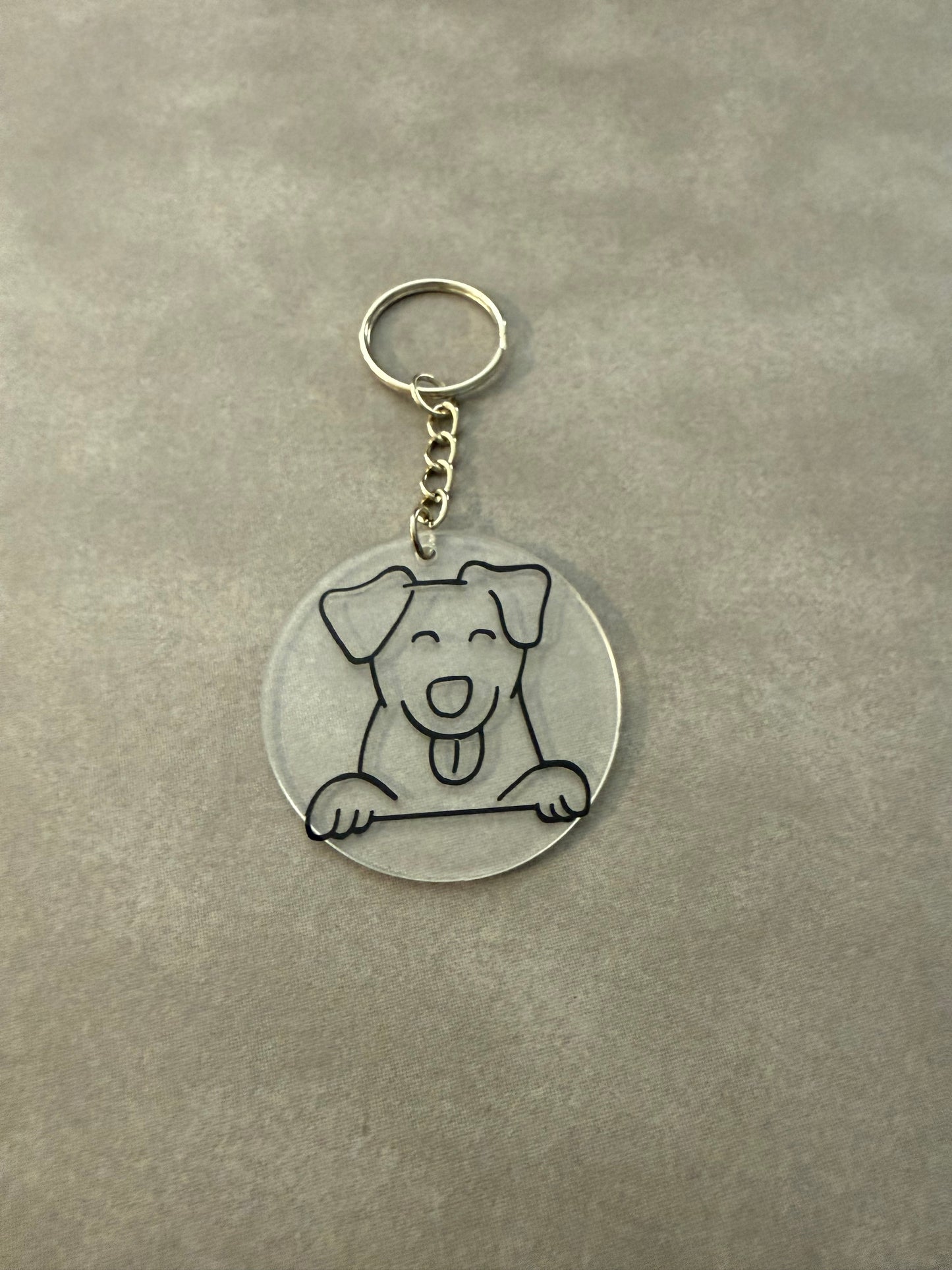 A small acrylic keychain with a round shape featuring a dog decoration, attached to a metal keyring.