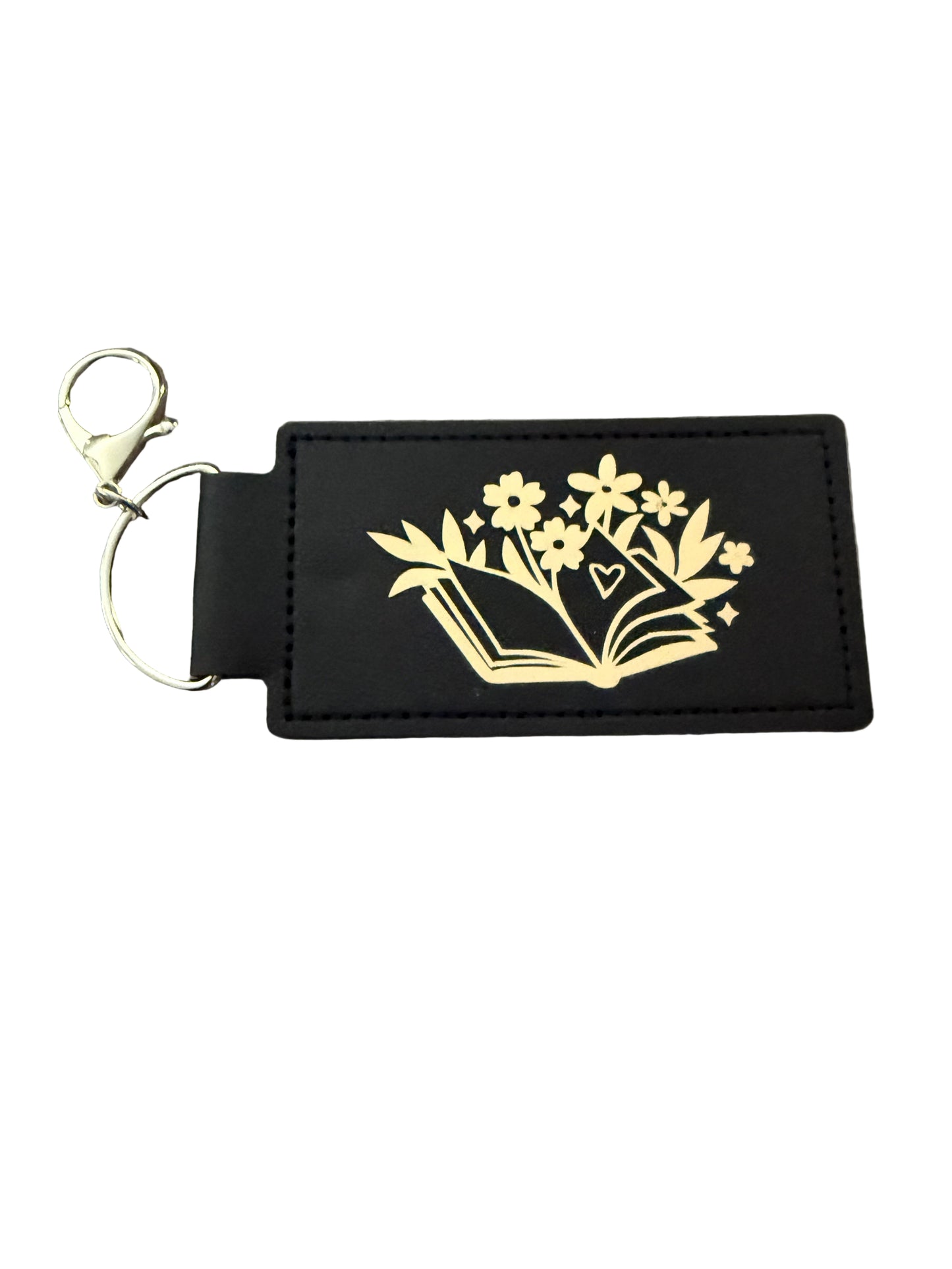 A black faux leather keychain with gold book and floral design, and a gold 'R' initial on reverse side, silver d-ring clasp Roxzell