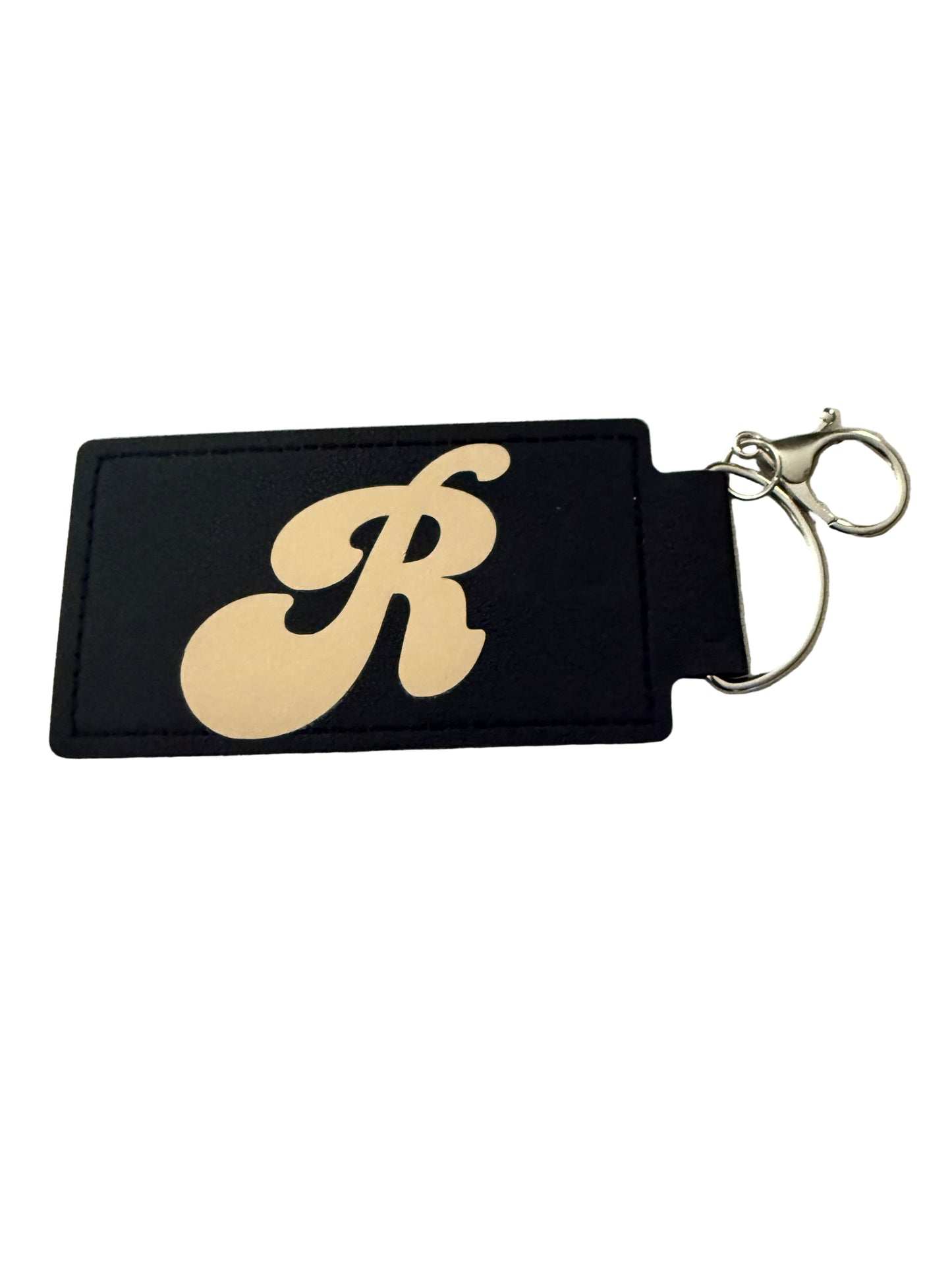 A black faux leather keychain with gold book and floral design, and a gold 'R' initial on reverse side silver d-ring clasp Roxzell