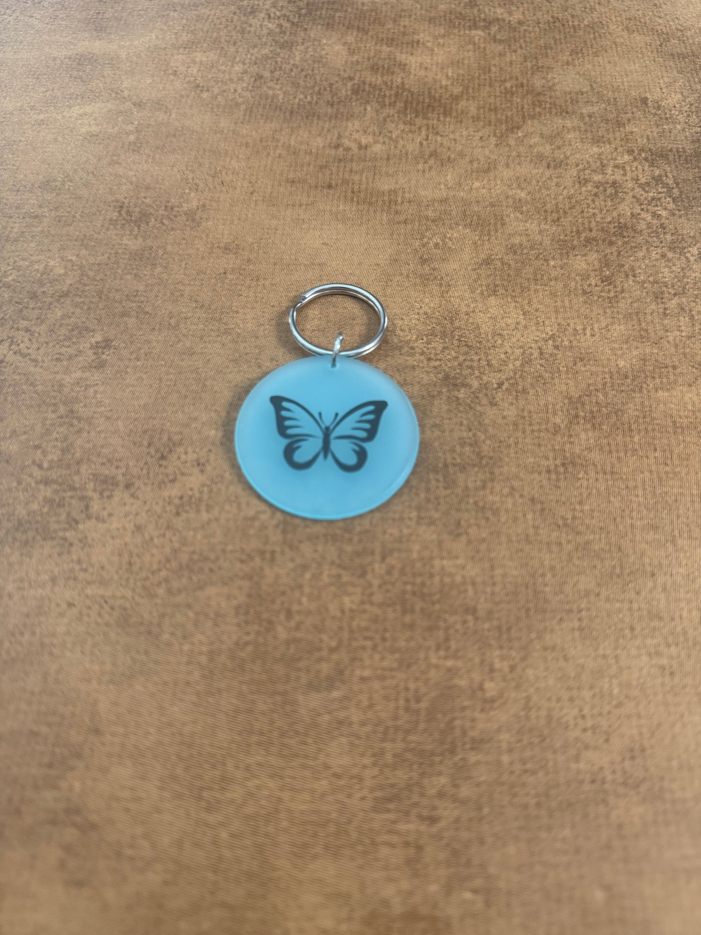 Blue acrylic butterfly keychain with "Spread Your Wings" on the reverse side.