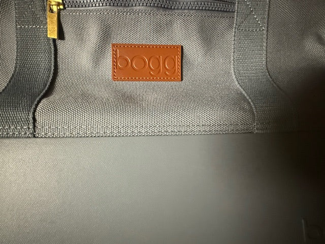 Close-up of a gray Bogg Weekender Bag with a leather brand tag displaying 'bogg' Roxzell