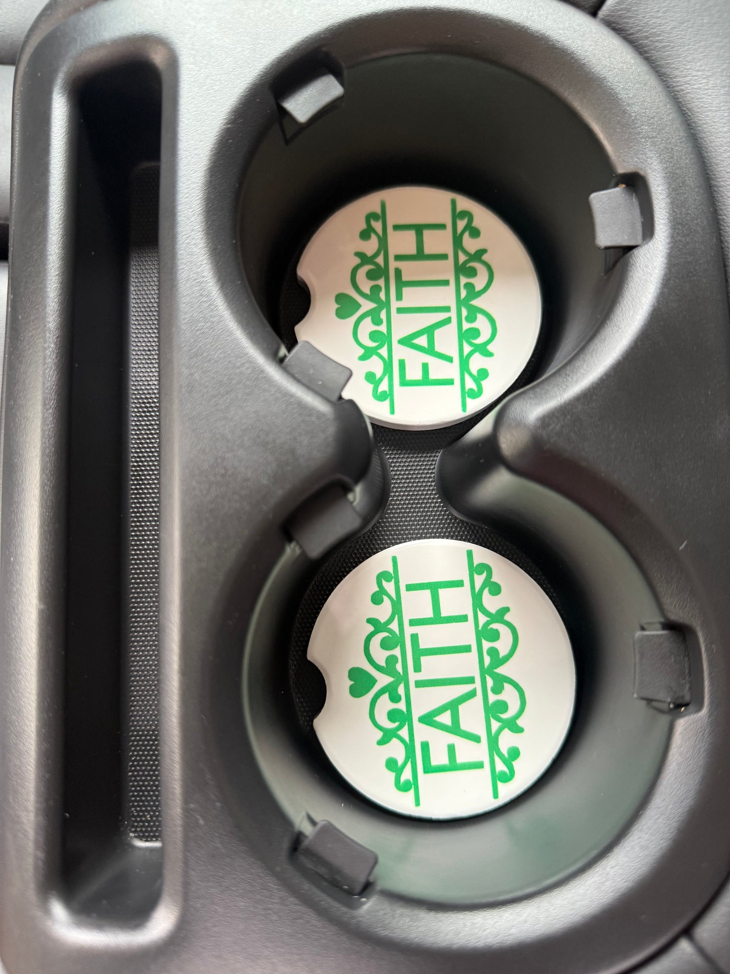 Two car cup holders with 'FAITH' car coasters inside, featuring green text.
