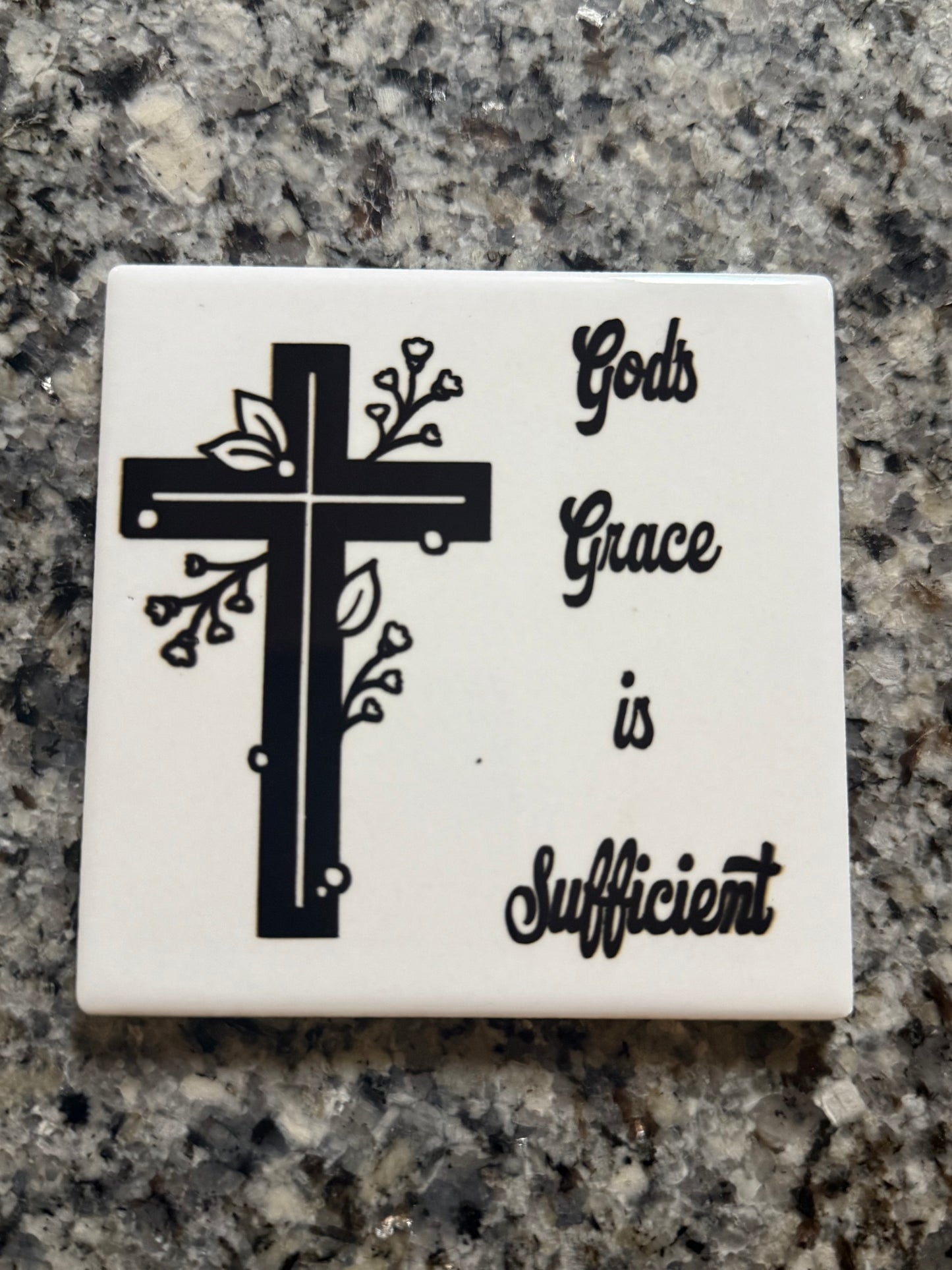 Square white ceramic coaster with black and white cross and words "God's Grace is Sufficient".