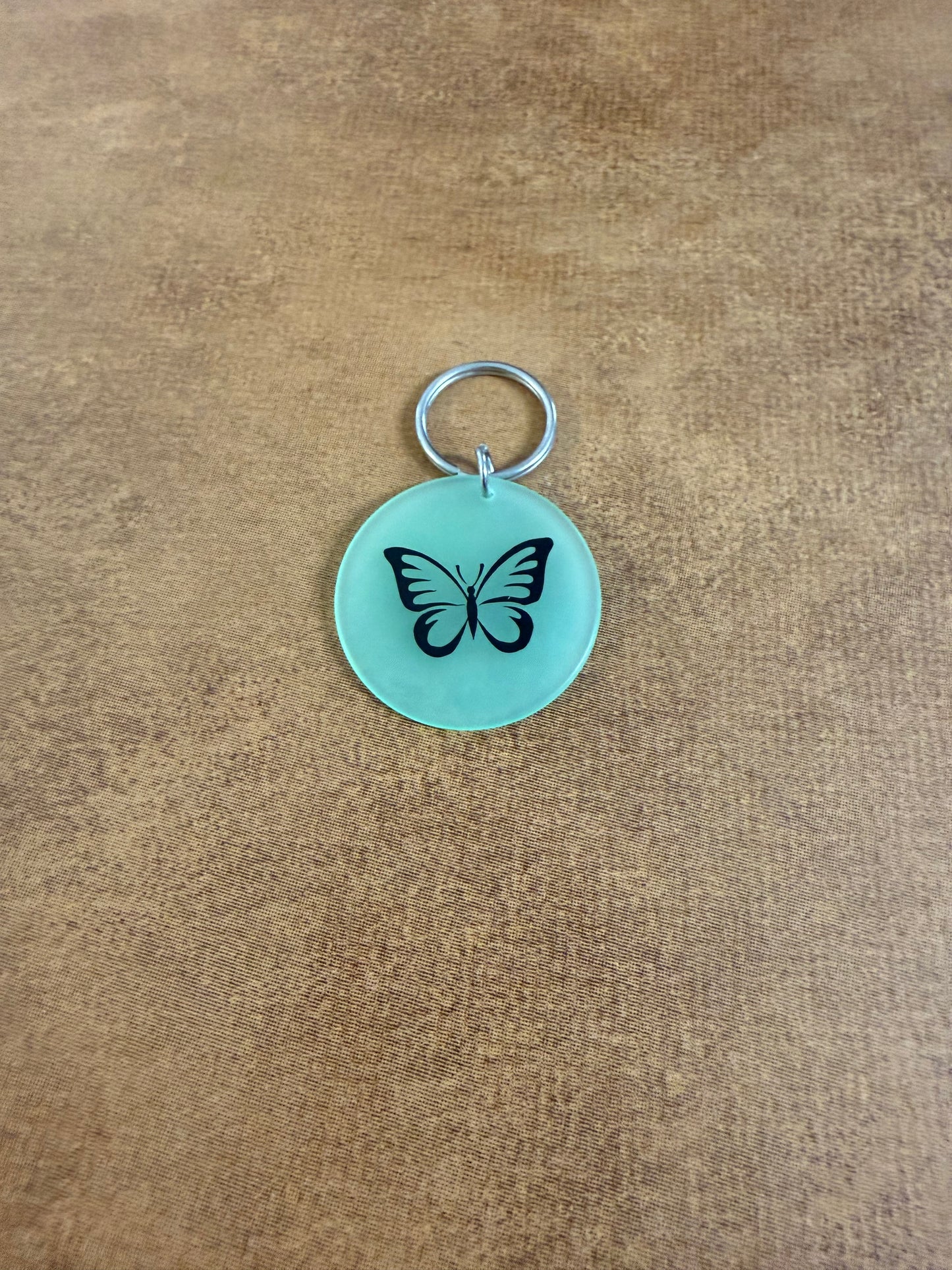 Green acrylic butterfly keychain with "Spread Your Wings" on the reverse side.