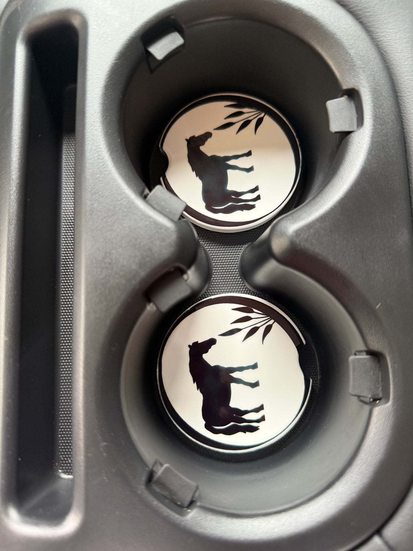 Two car cup holders with decorative coasters featuring a horse design.