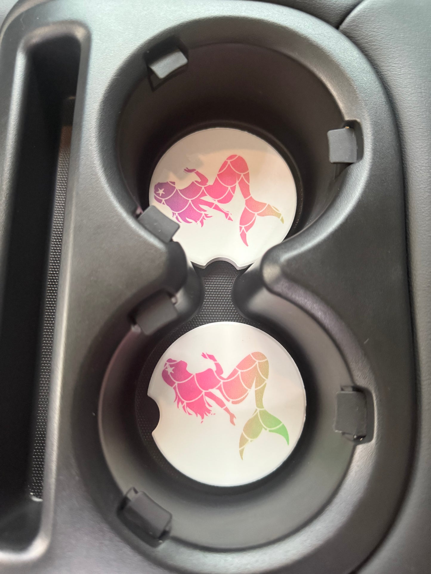 Car cup holder with two decorative car coasters featuring mermaid designs.