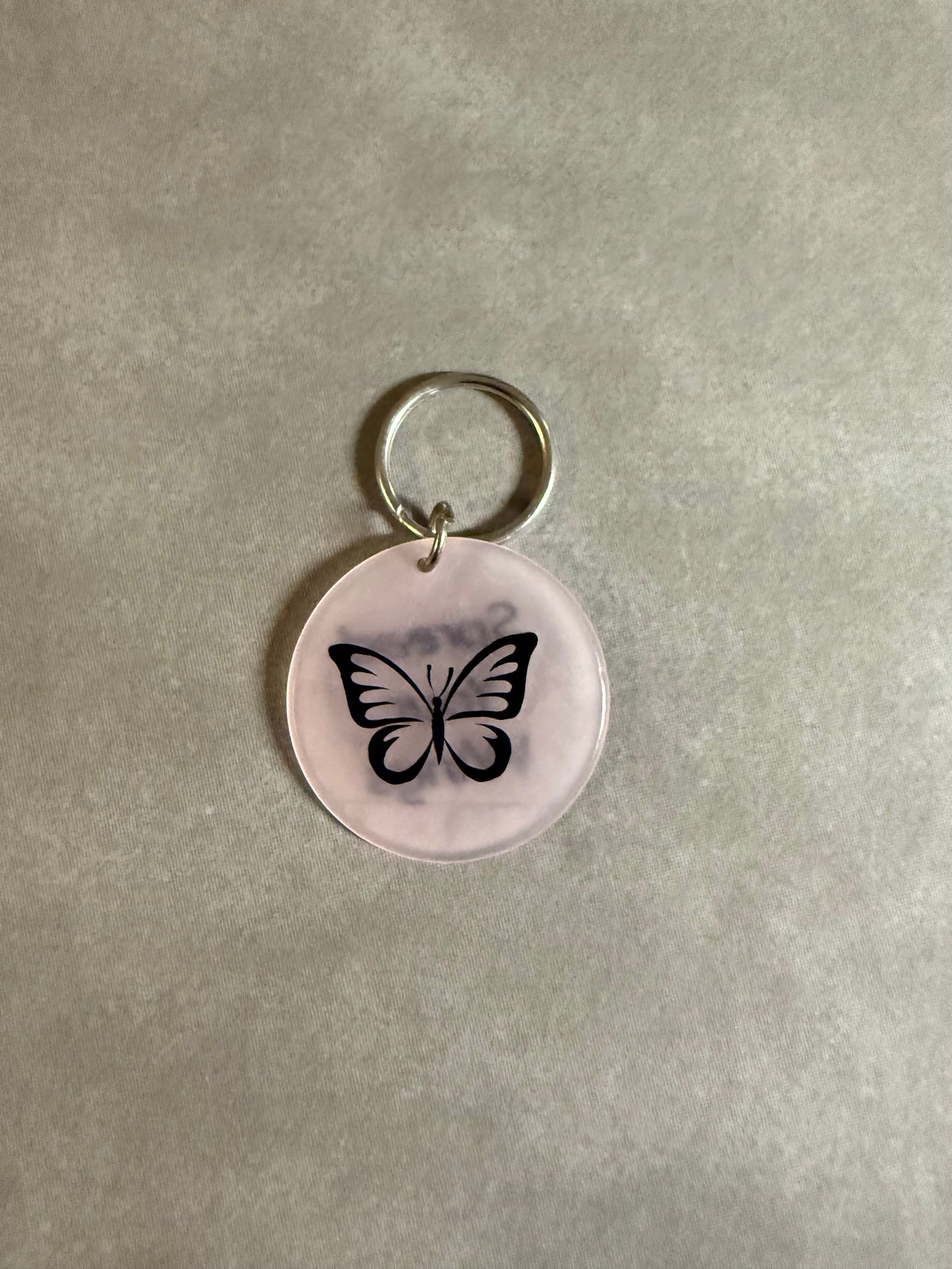 Pink acrylic butterfly keychain with "Spread Your Wings" on the reverse side.