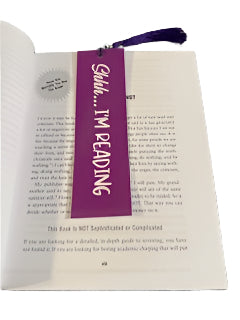 Book with a purple bookmark labeled 'Shhh... I'm Reading' on a white surface.