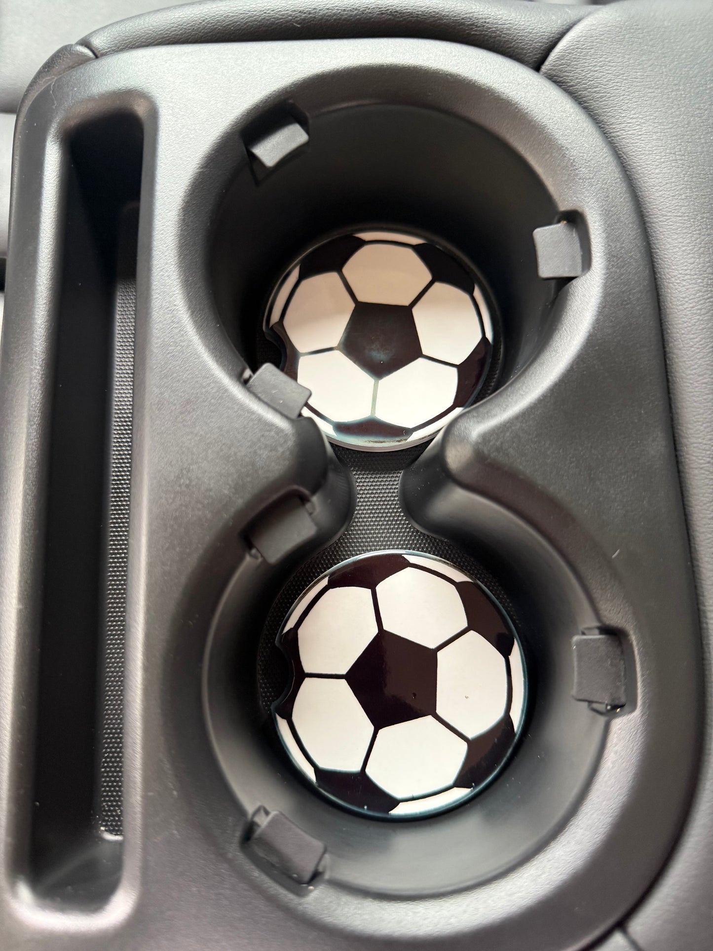 Two soccer ball-shaped designed car coasters in a vehicle's cup holder tray Roxzell