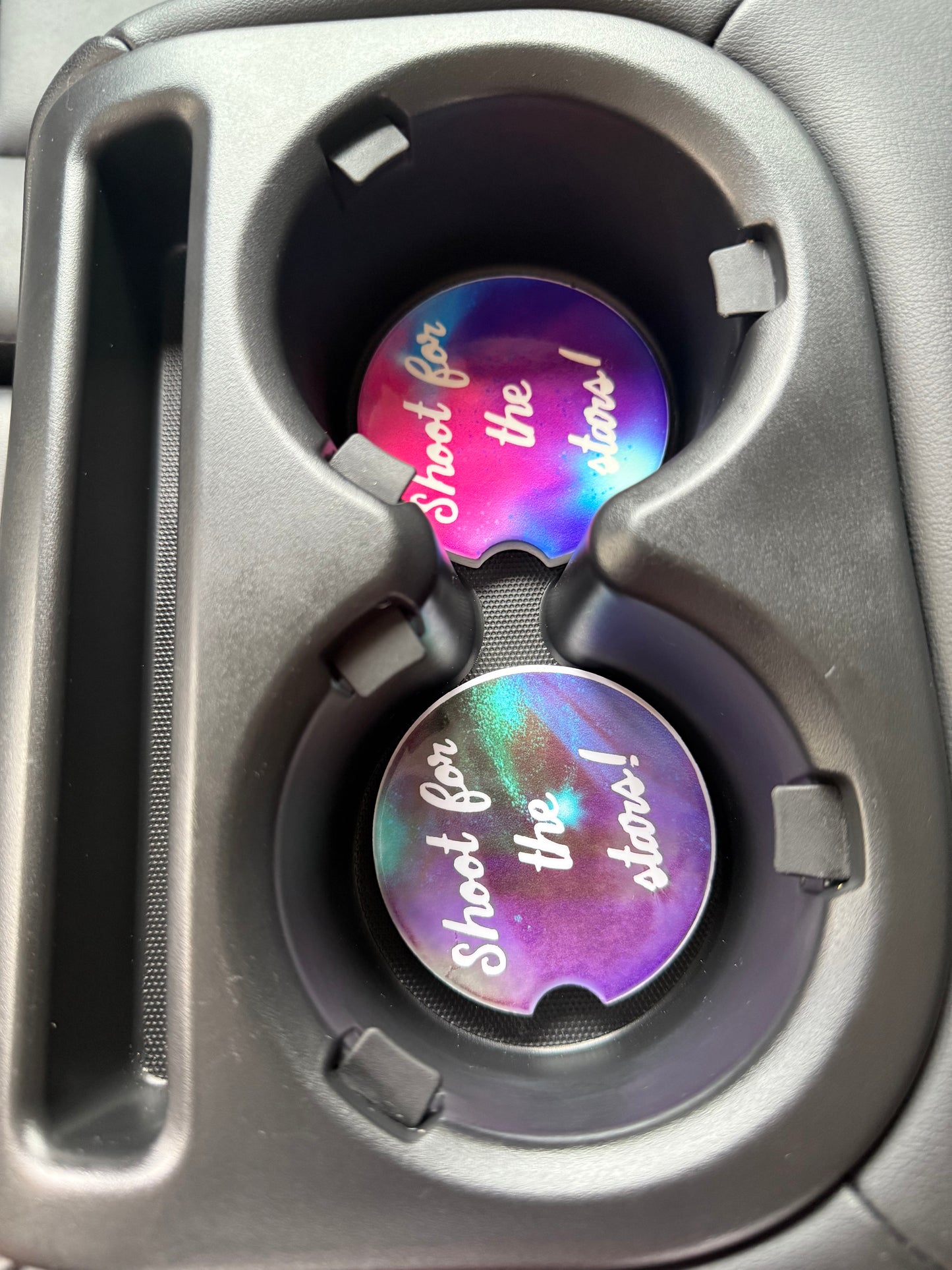 Two colorful car cup coasters with 'Shot the Stars' design inside a vehicle's cup holders Roxzell
