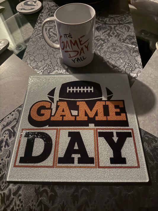 Decorative kitchen board with "GAME DAY" design for football fans and I'ts Game Day Yall coffee mug on a gray textured table runner, Roxzell