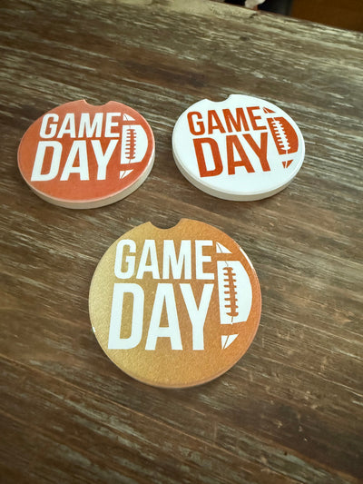 Three Roxzell customized car coaters. Each coaster has a game day design.  One coaster is dark brown with white writing, the second coaster is white with dark brown writing.  The third coaster is light brown with white writing.