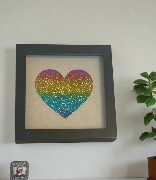 8 x 8 black shadow box with multicolor glitter heart design on tan canvas.