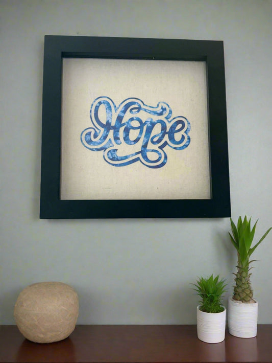 8 x 8 Black frame shadow box designed with the work "Hope" in blue on tan canvas.