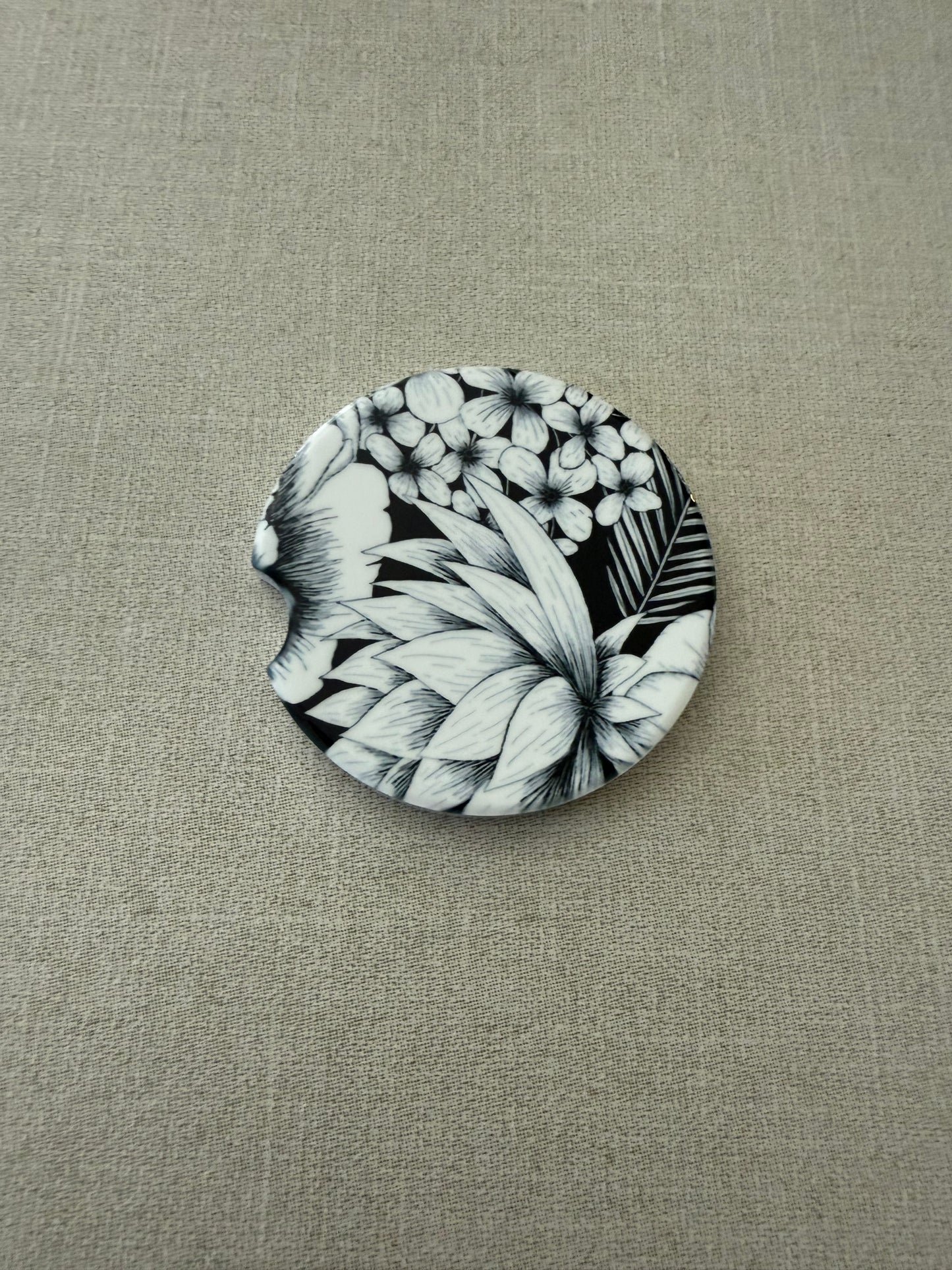 2.5" round ceramic car coaster designed with black and white botanical flowers.