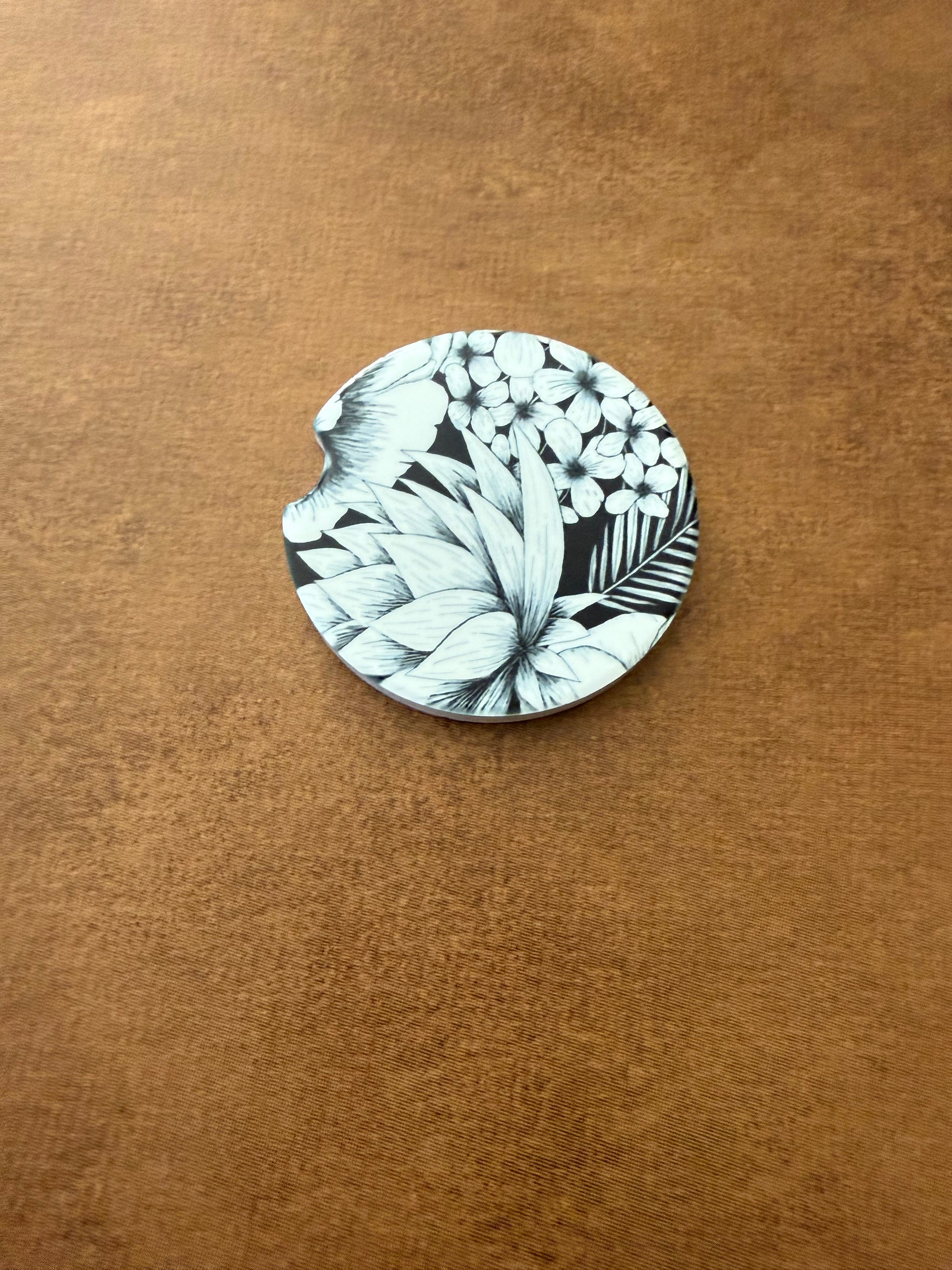 2.5" round ceramic car coaster designed with black and white botanical flowers.