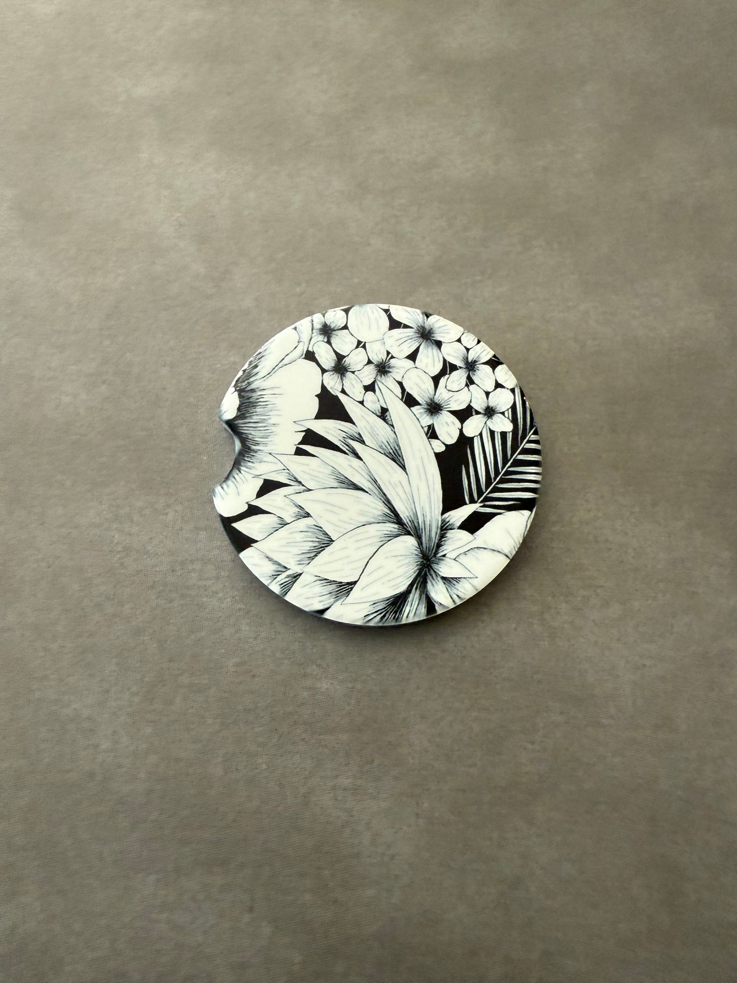 2.5" round ceramic car coaster designed with black and white botanical flowers.