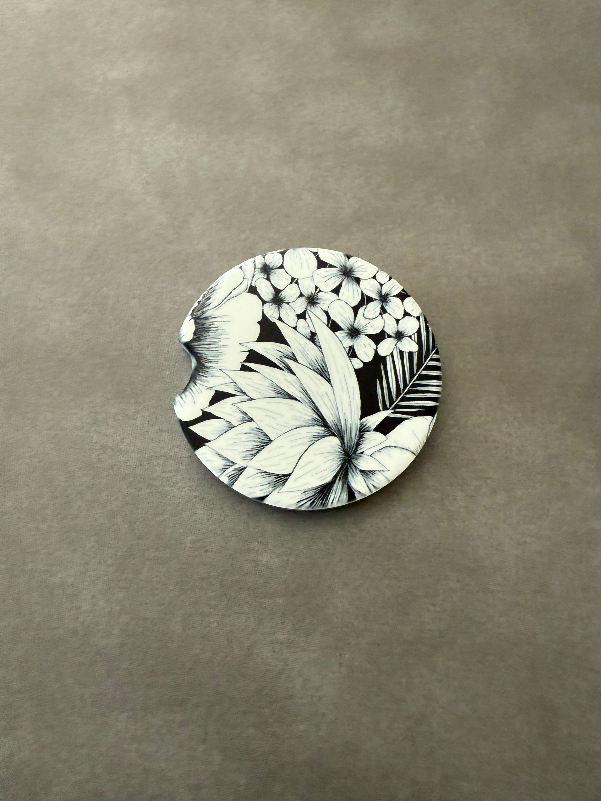 2.5" round ceramic car coaster designed with black and white botanical flowers.