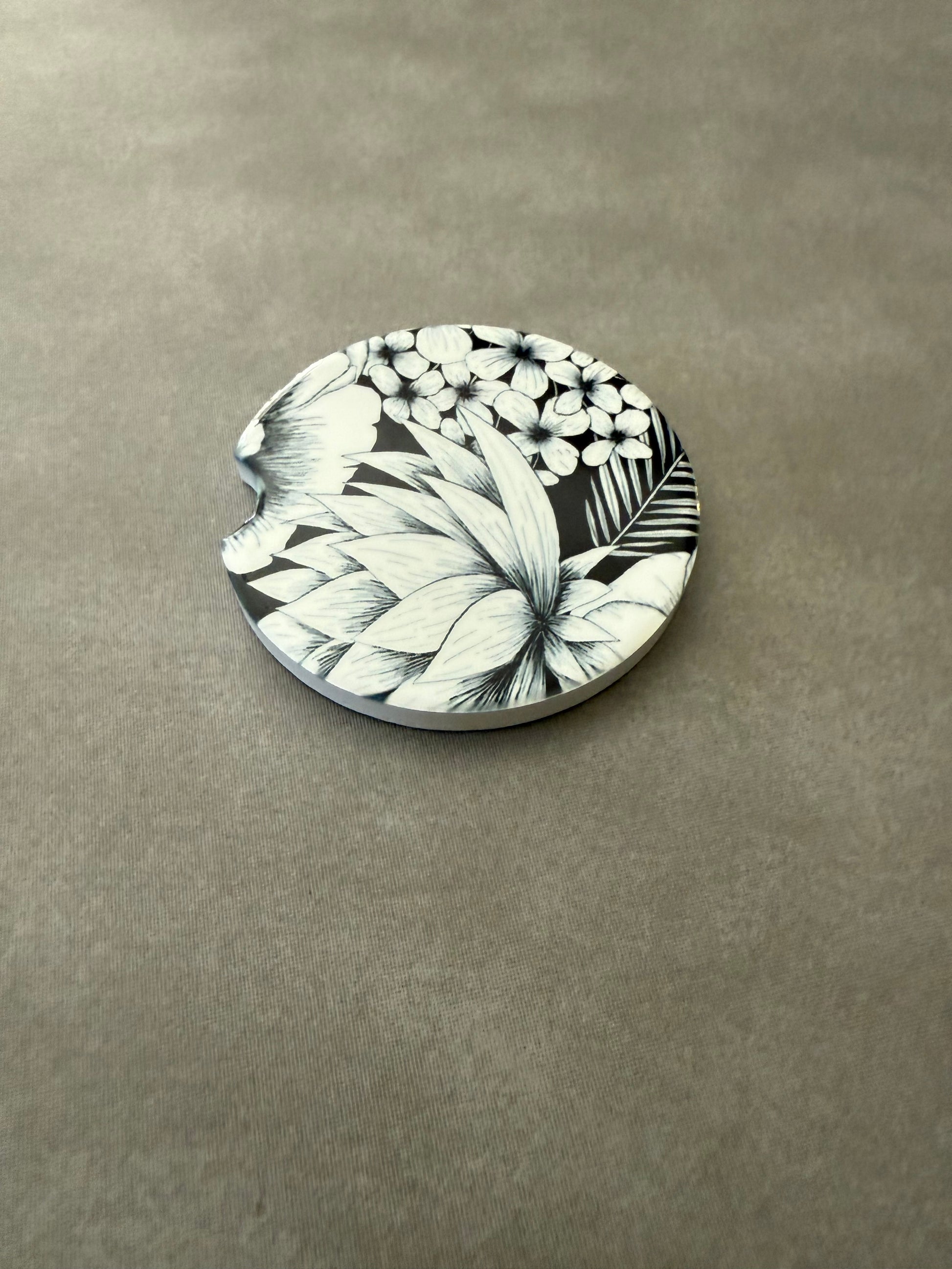 2.5" round ceramic car coaster designed with black and white botanical flowers.