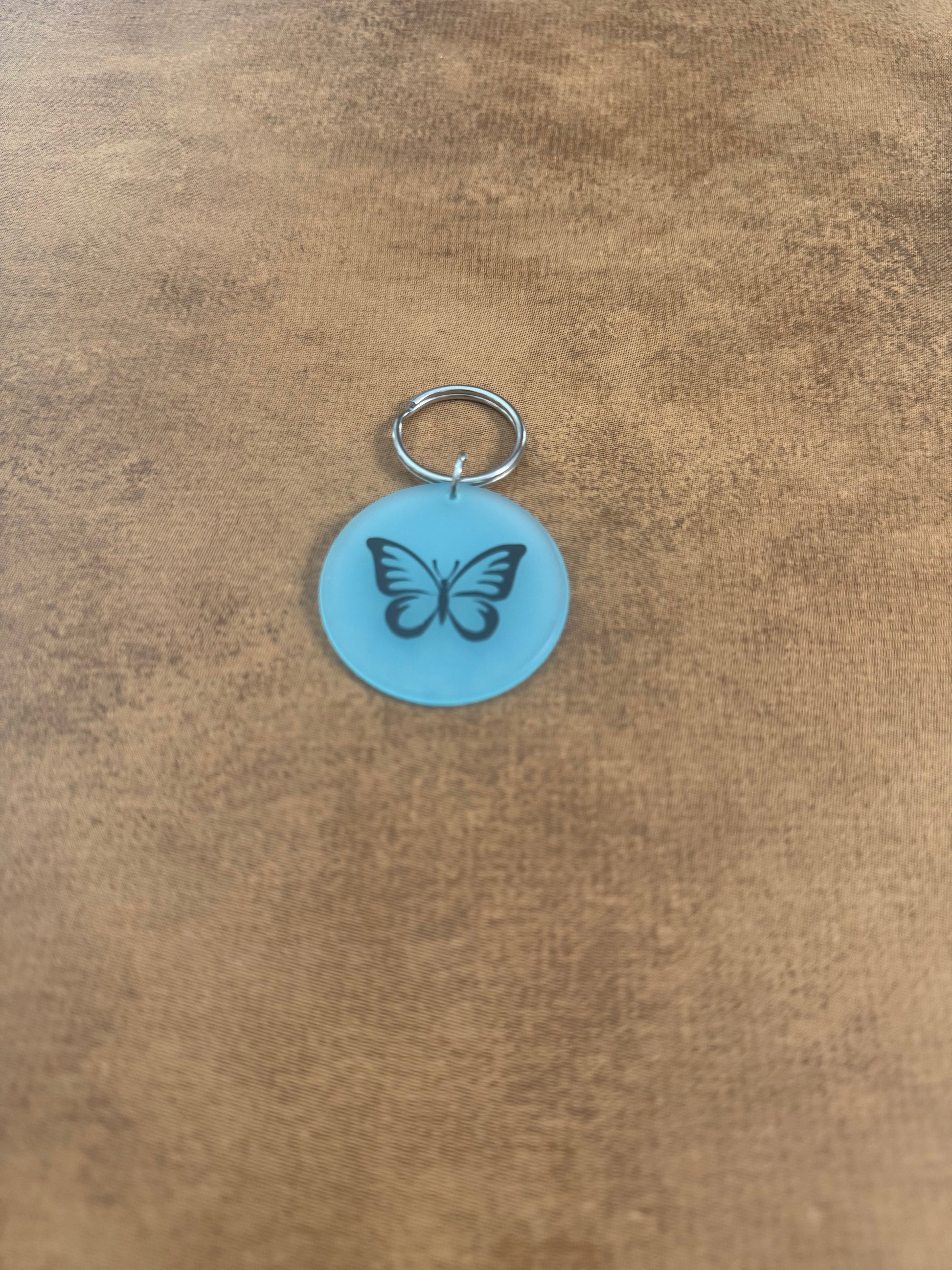 Blue acrylic butterfly keychain with "Spread Your Wings" on the reverse side.