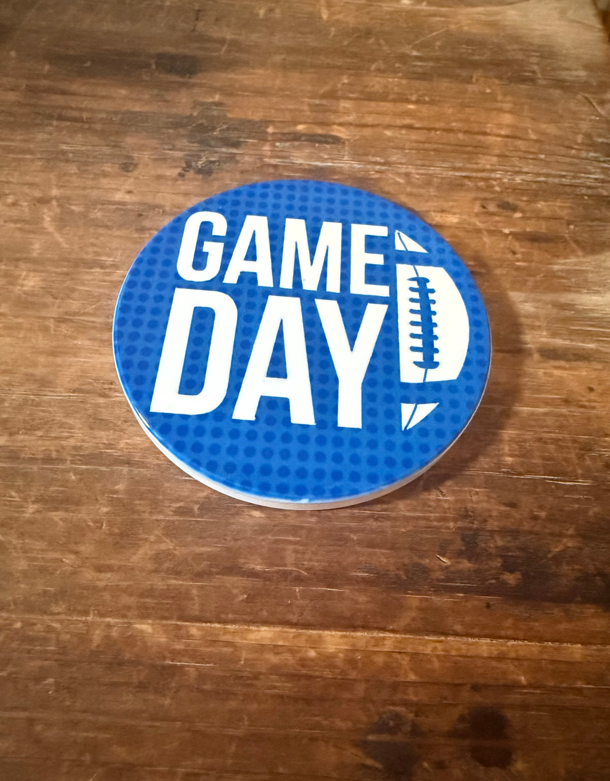 Circular blue coaster with dotted background and white “GAME DAY” lettering featuring football‑style D. Roxzell