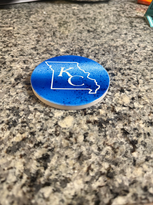 Blue and white round ceramic coaster with KC designed inside the shape of Missouri.