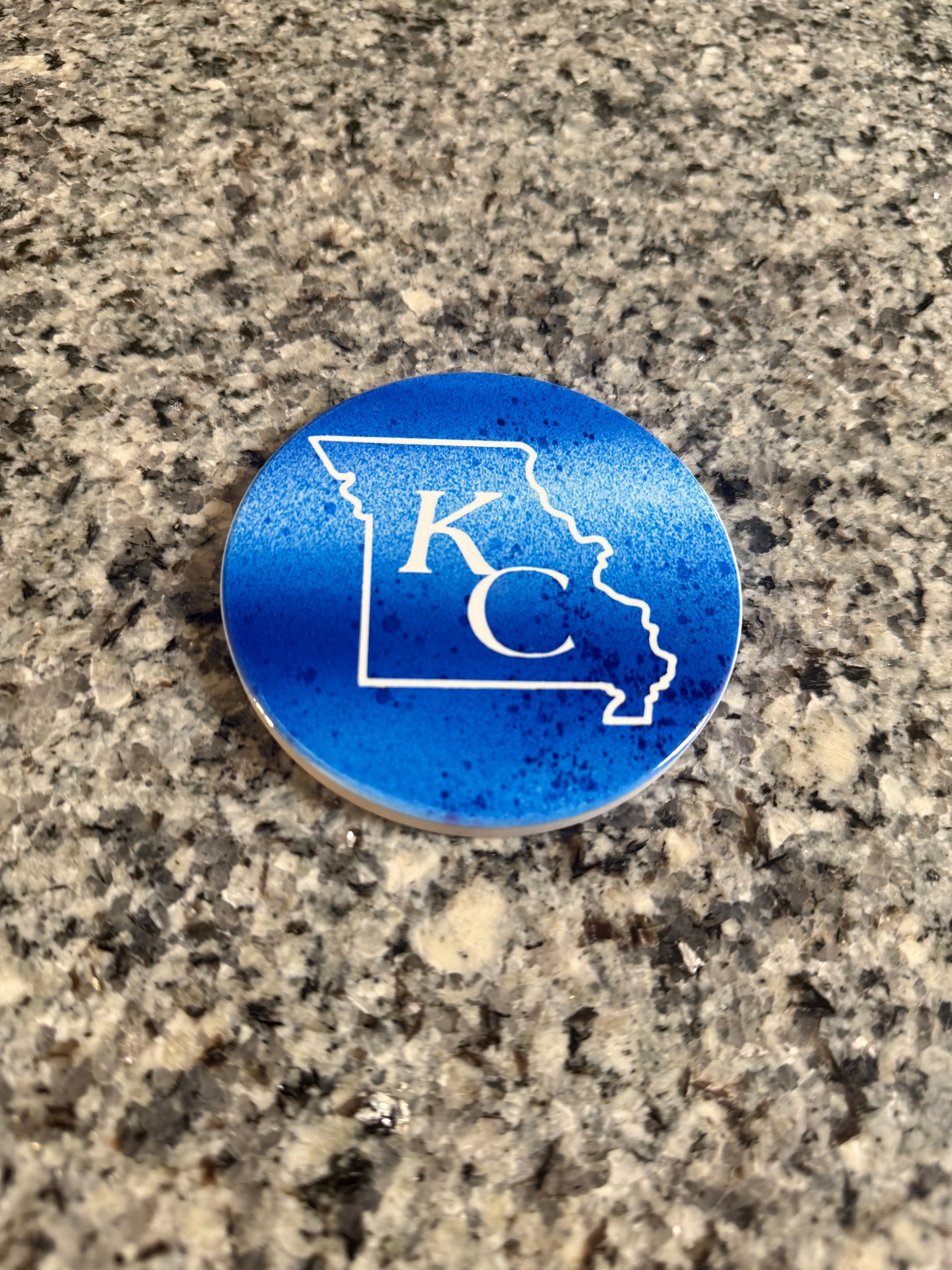 Blue and white round ceramic coaster with KC designed inside the shape of Missouri.