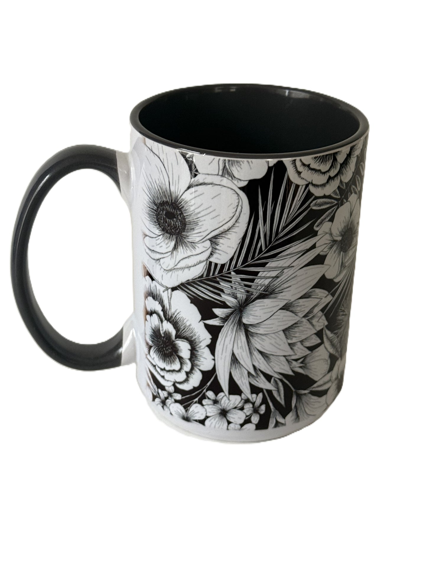 A close-up of a black ceramic mug featuring detailed white floral illustrations and a black handle. Roxzell