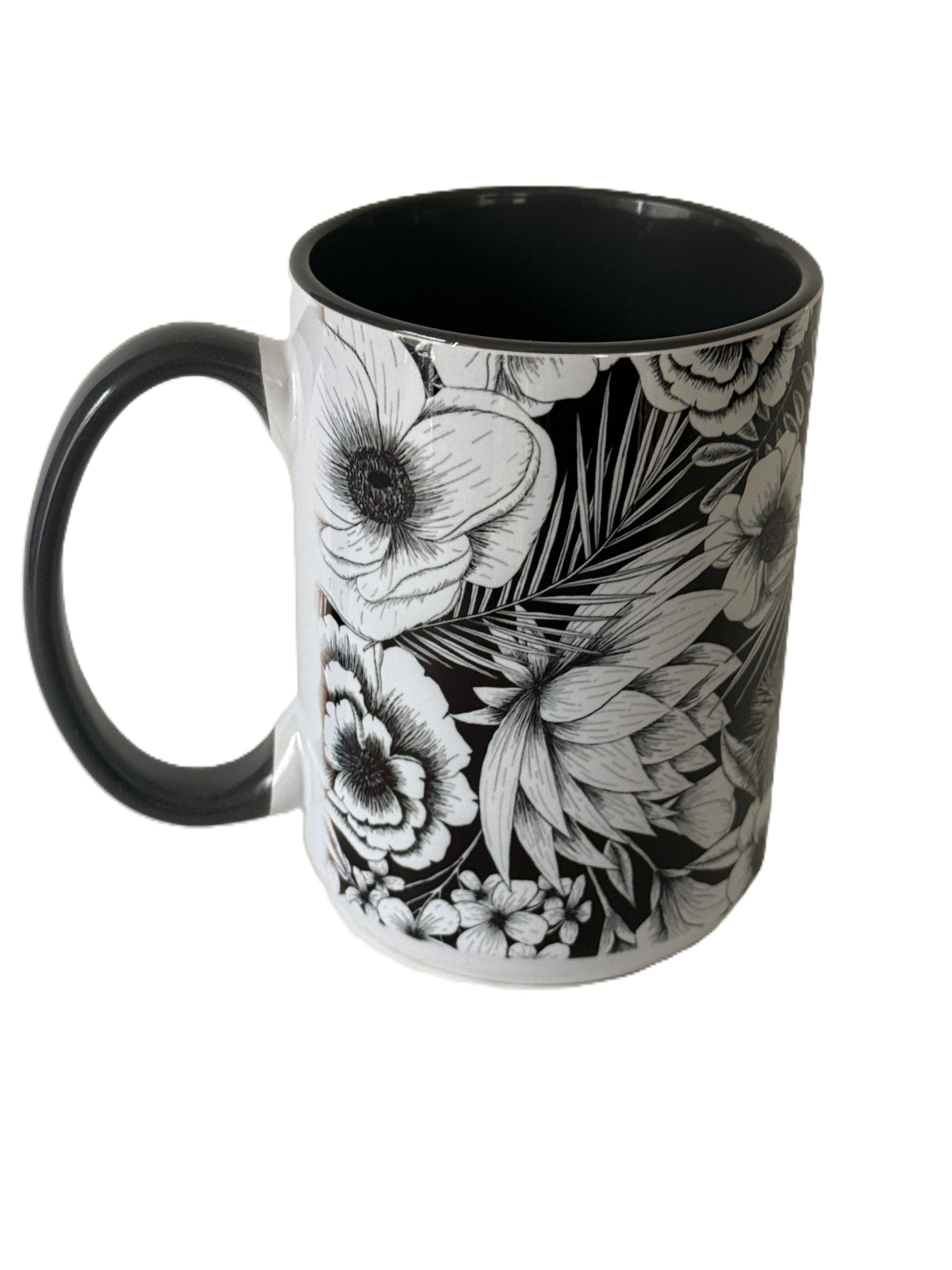 A close-up of a black ceramic mug featuring detailed white floral illustrations and a black handle. Roxzell