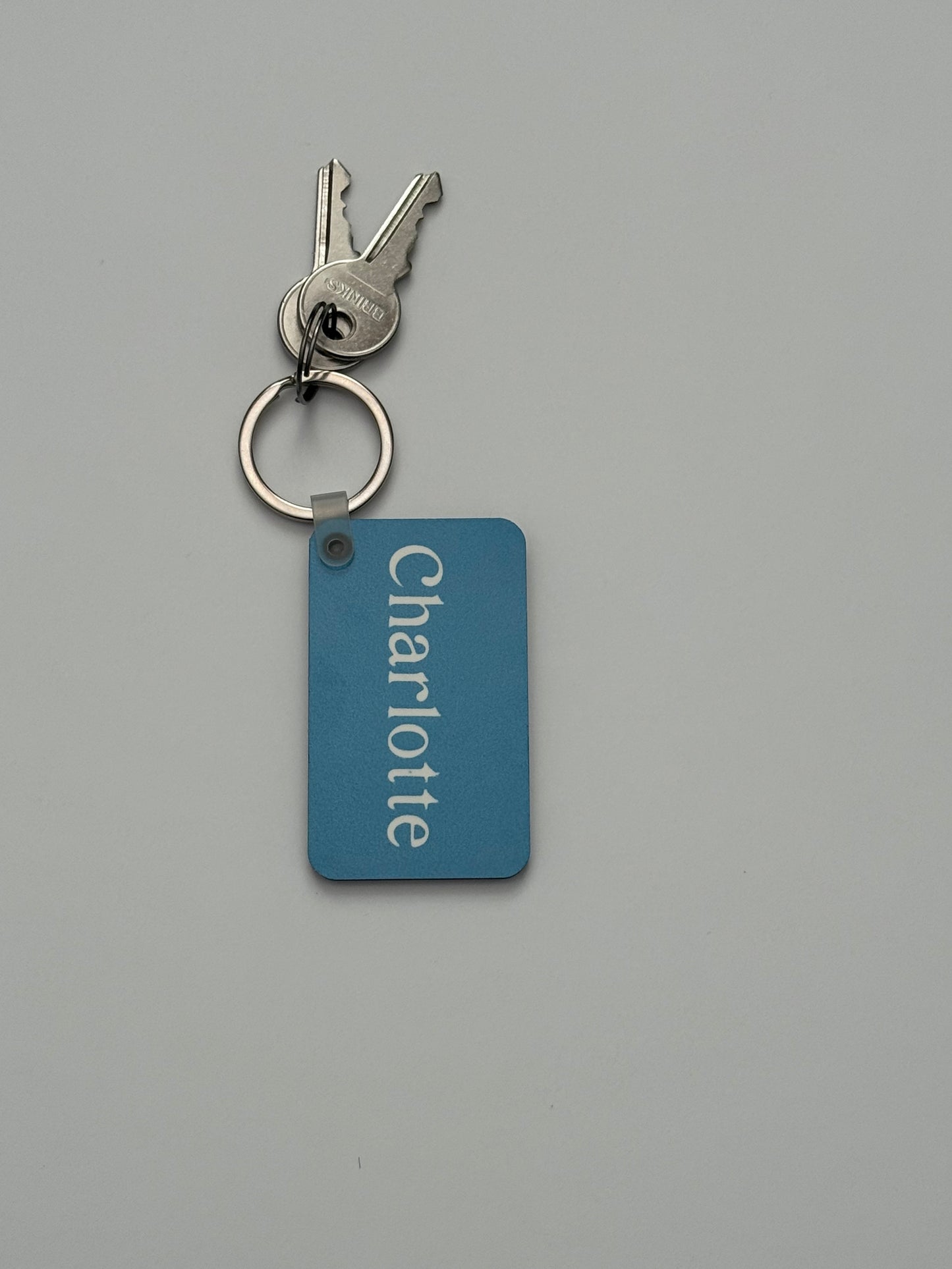 A light blue keychain with name 'Charlotte' on a light gray background. Roxzell