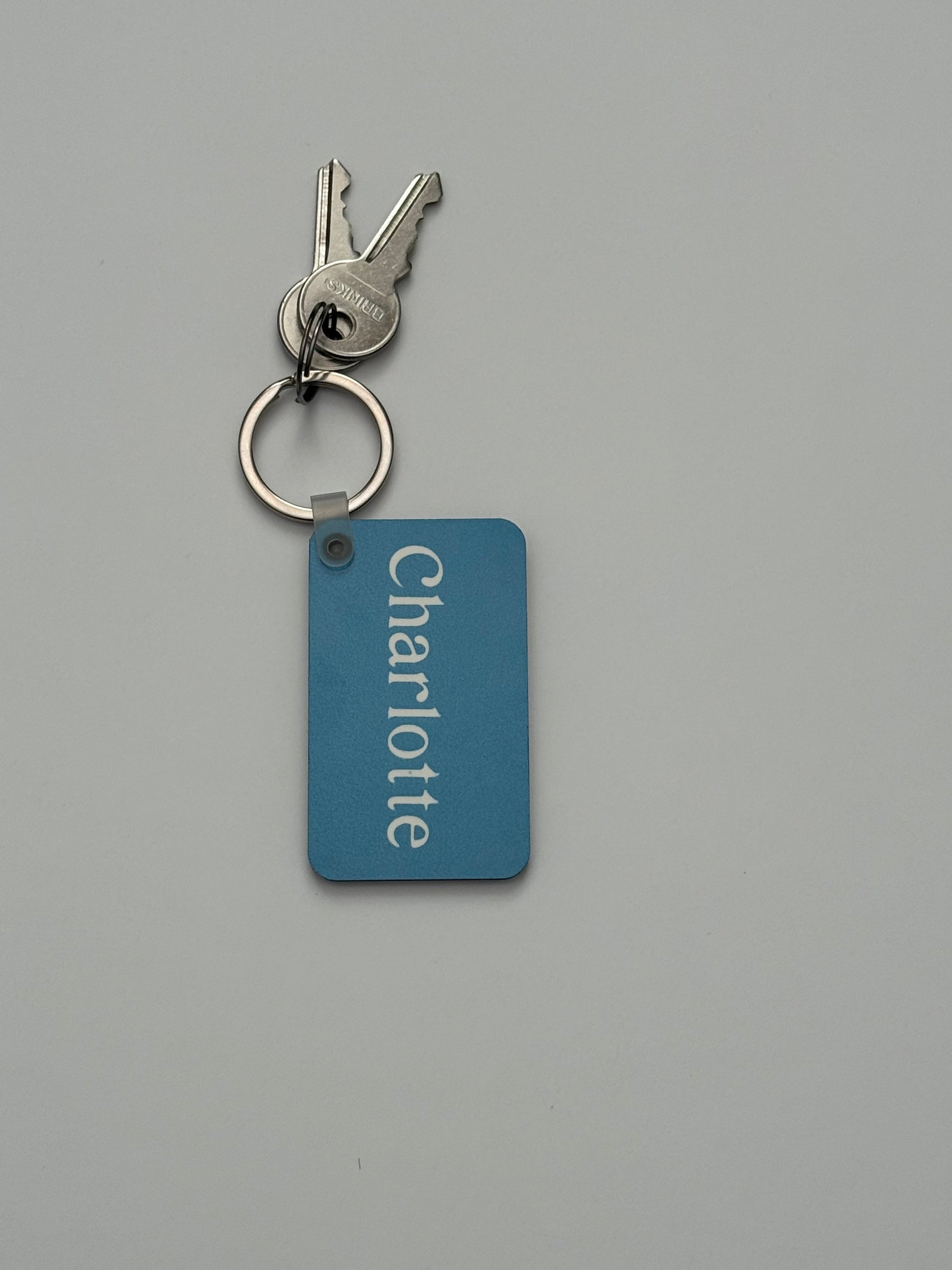 A light blue keychain with name 'Charlotte' on a light gray background. Roxzell