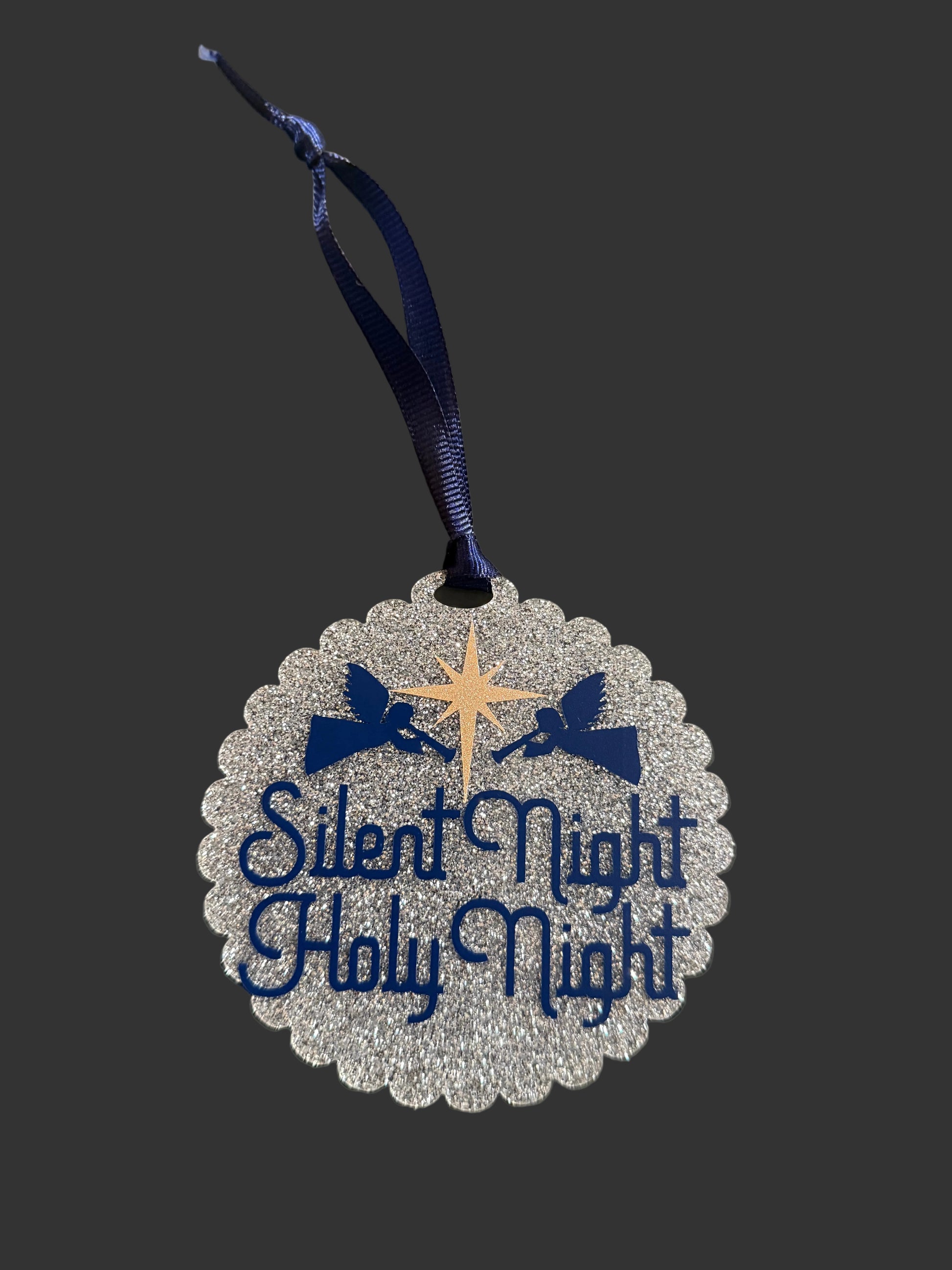 Decorative ornament with 'Silent Night Holy Night' text and blue ribbon on a neutral background