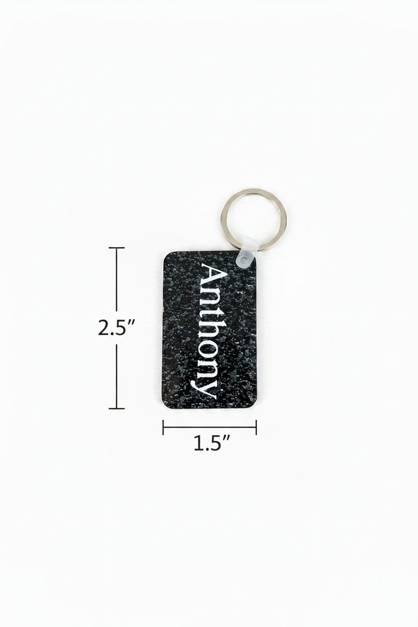 Detailed view of custom keychain showing the names “Anthony” in white text black keychain, highlighting texture and craftsmanship. 2.5" dimension arrow on the left side of keychain and 1.5" dimension arrow below the keychain.