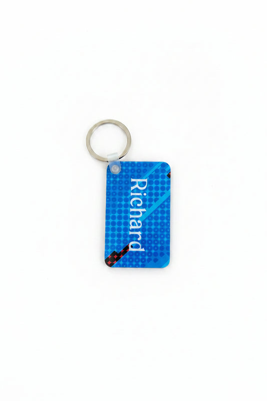 Personalized blue keychain with white “Richard” text and dotted pattern, attached to a silver ring on a white background. Roxzell