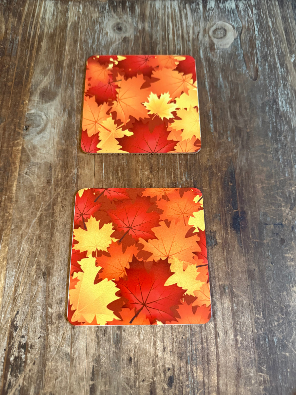 Set of 2 square drink coasters with autumn maple leaf print in red, orange and yellow. Roxzell
