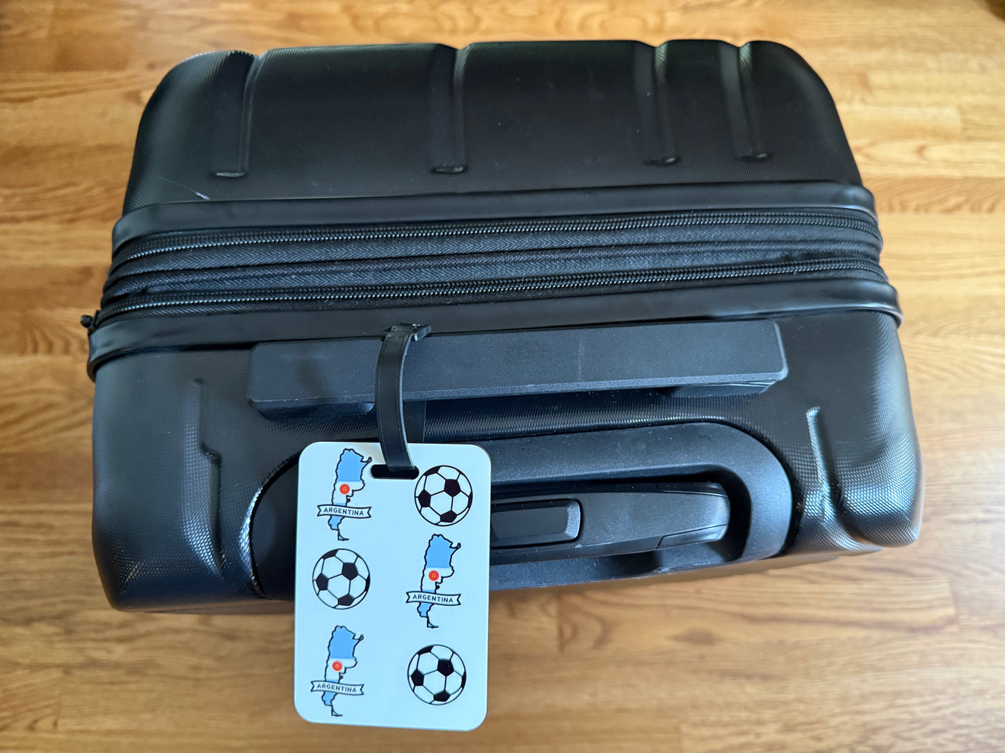 White luggage tag with alternating soccer balls and blue Argentina map outlines. Roxzell