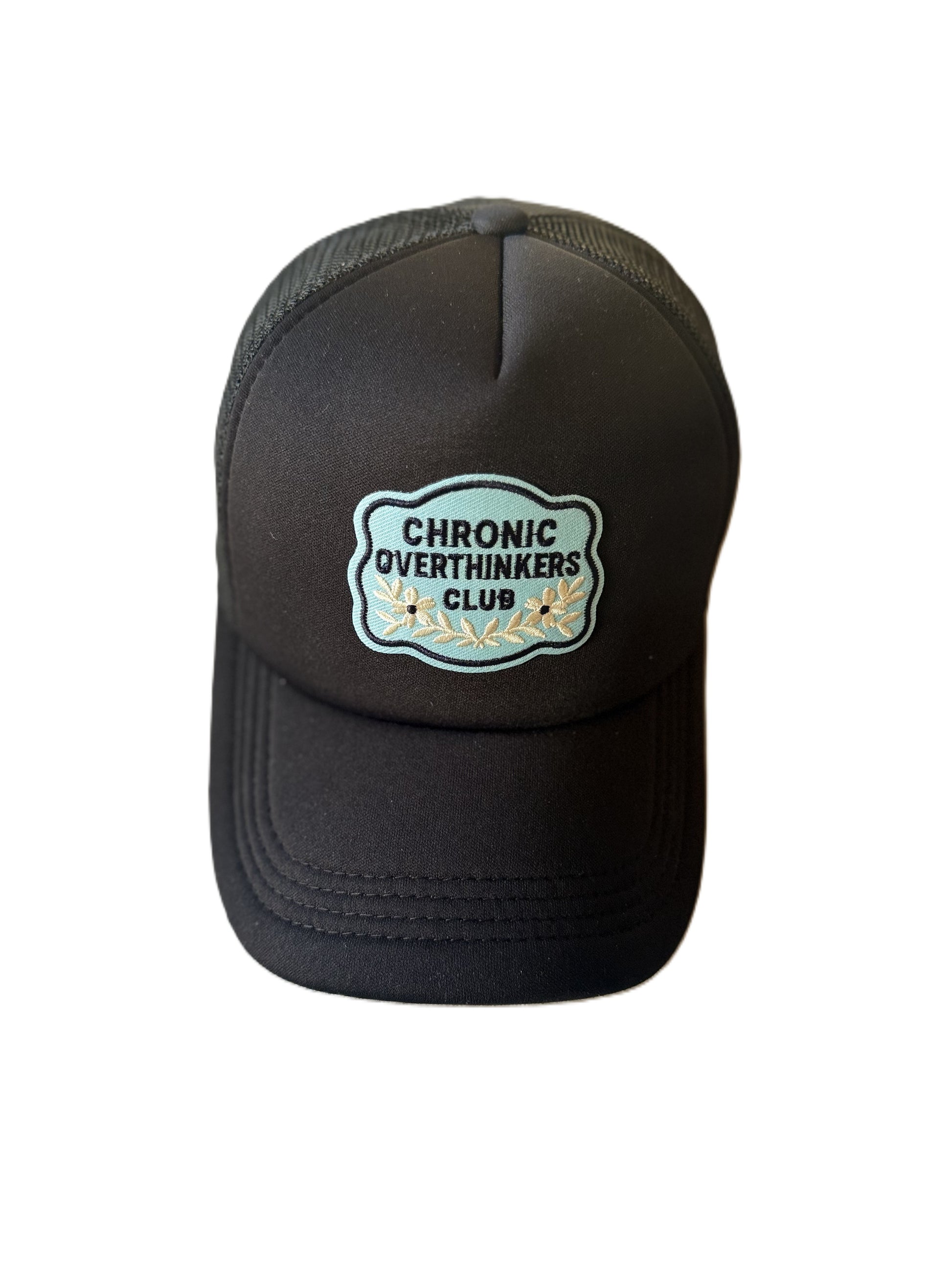 Front view of black trucker hat with “Chronic Overthinkers Club” embroidered patch. Roxzell