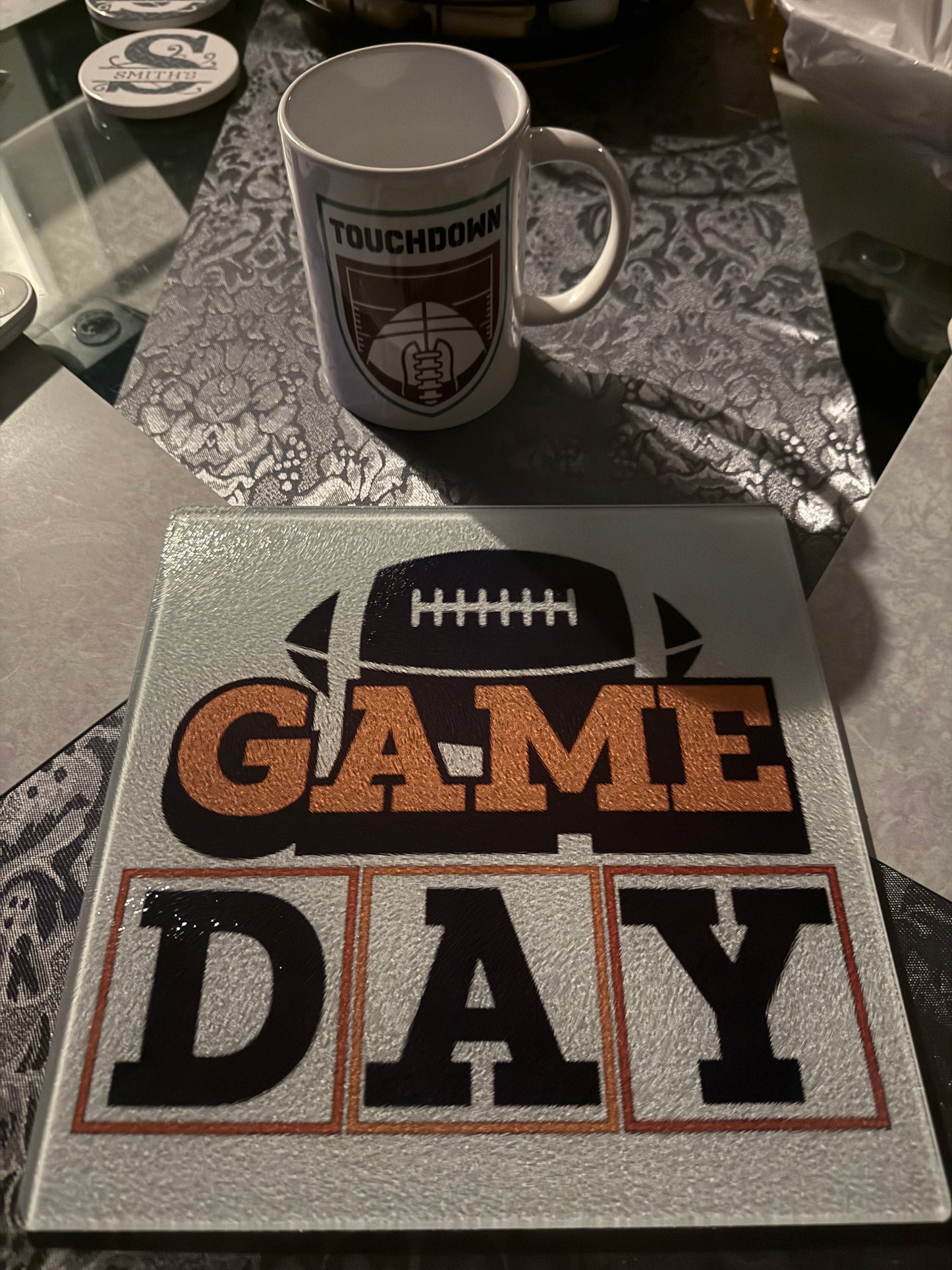 Tailgate-ready cutting board with football graphic and bold orange Game Day text, white coffee mug with touchdown design, Roxzell