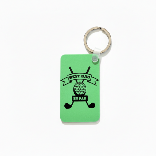 Green keychain with black design featuring crossed golf clubs, a golf ball, and the phrase “Best Dad by Par” printed in bold lettering. 2.5" dimension shown on the left side and 1.5" dimension arrow shown below keychain. Roxzell
