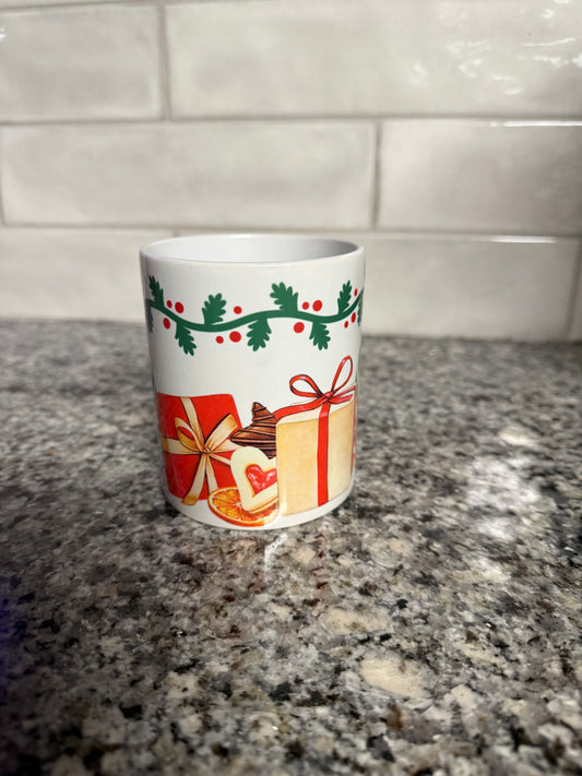Festive ceramic Christmas mug with gift boxes, holly, and cookies on granite countertop