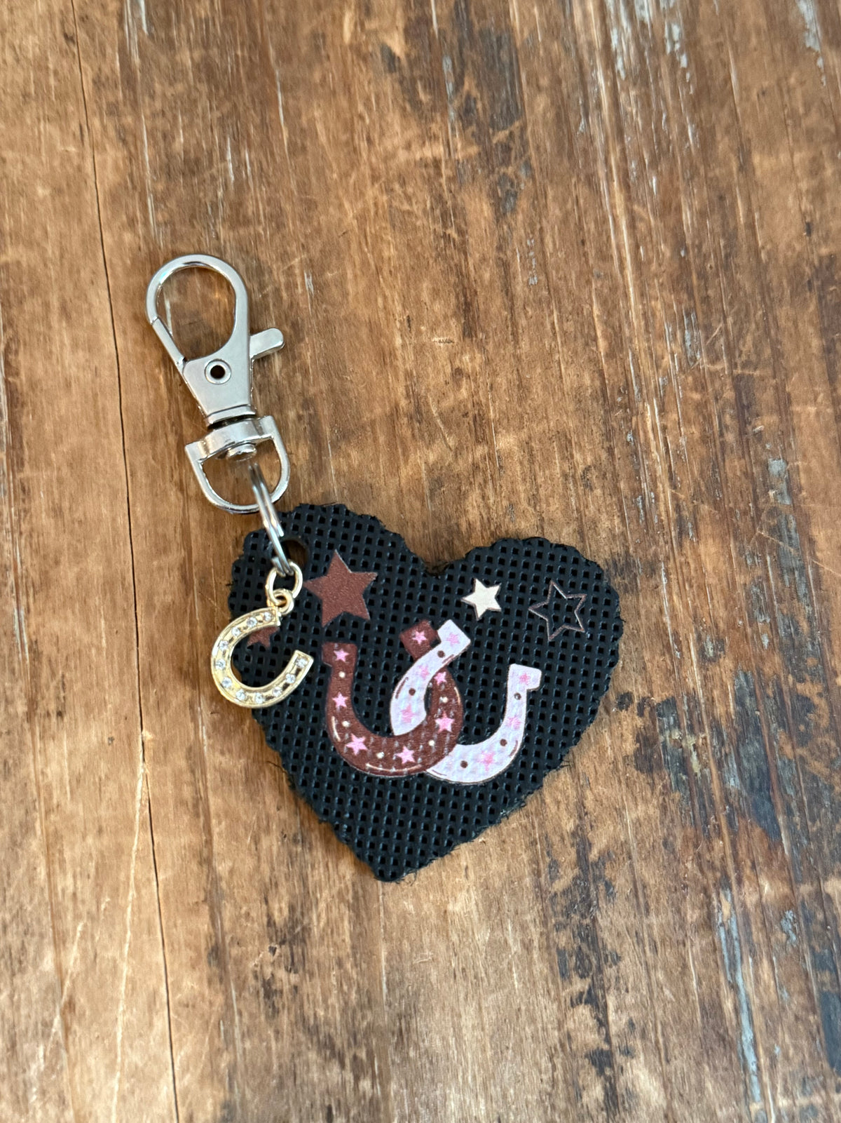 Black heart bag charm with pink and brown horseshoes, stars, dangling horseshoe accent, and silver-tone clasp