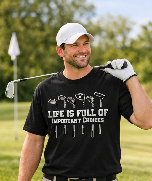 Man on a golf course holding a golf club and wearing a black t-shirt with a humorous quote, "Life is Full of Important Choices" written between different types of gold clubs. Roxzell