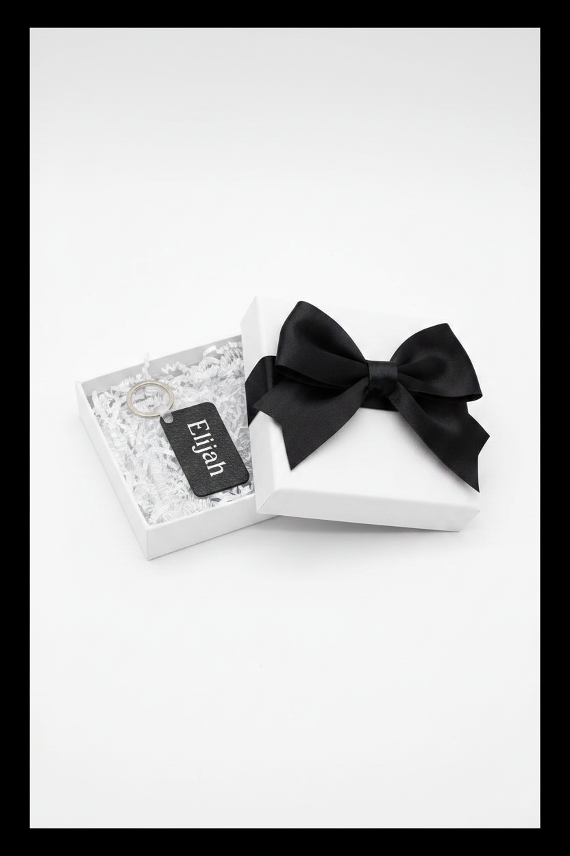 Personalized keychain with name Elijah printed in white in a white gift box with black bow on a white background with black border. Roxzell