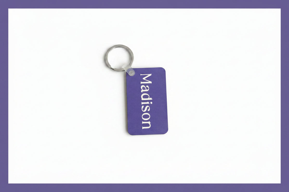 Personalized Madison keychain with white name print on a white background with a purple border. Roxzell