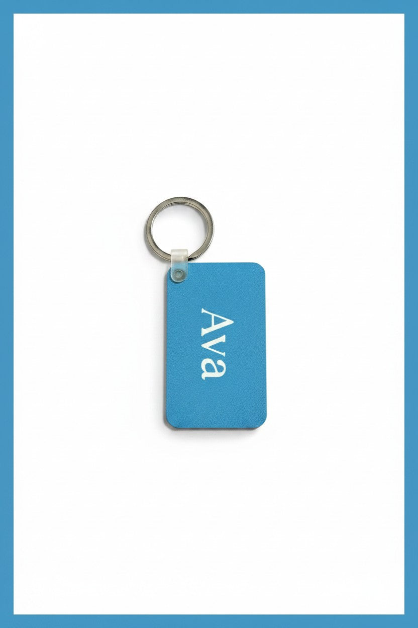A rectangular blue keychain tag with the name 'Ava' printed in white, attached to a silver metal key ring, shown on a white background with a blue border.