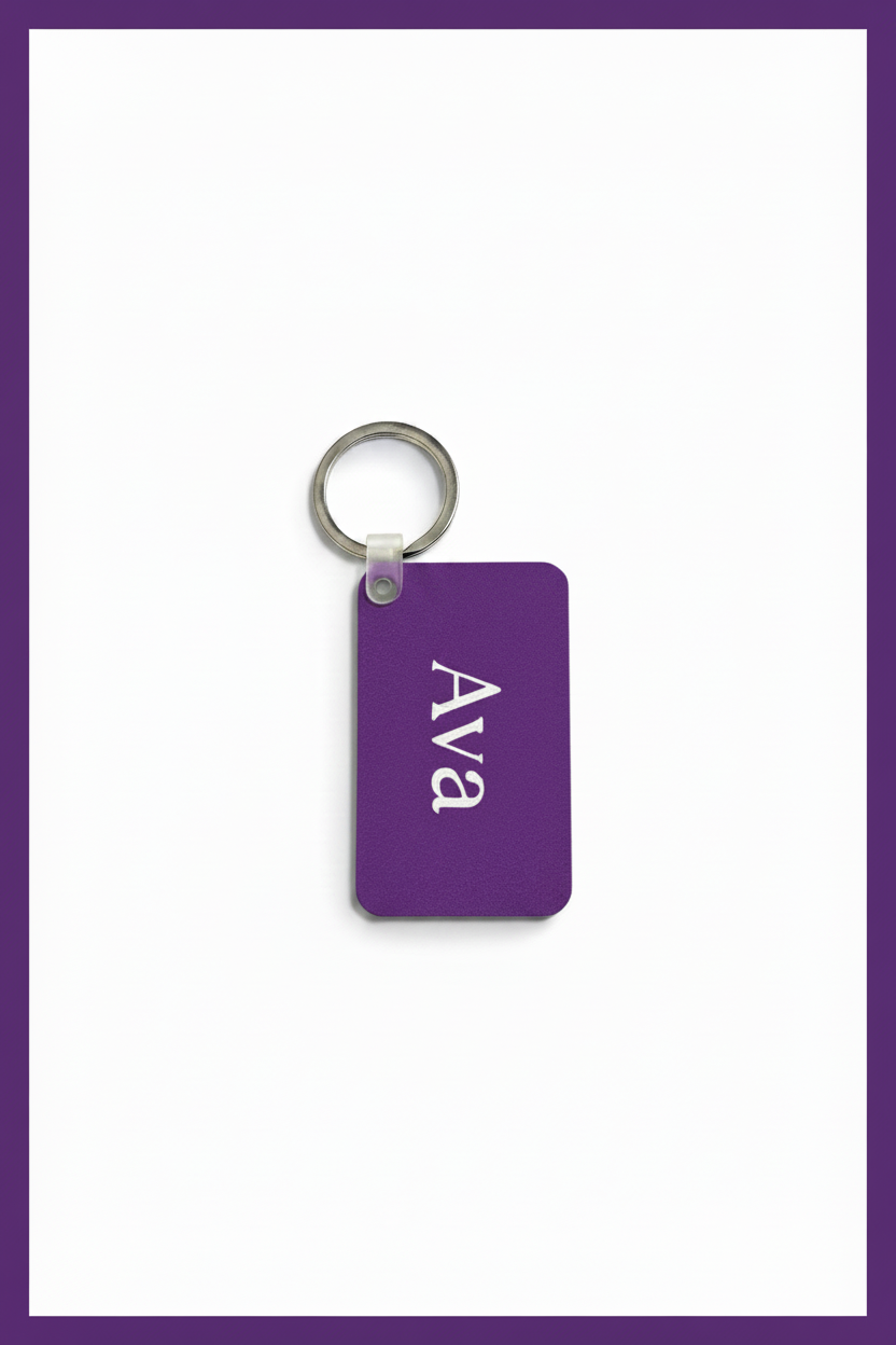 A purple rectangular keychain tag with the name 'Ava' printed in white serif letters, attached to a silver metal key ring, shown on a white background with a purple border.
