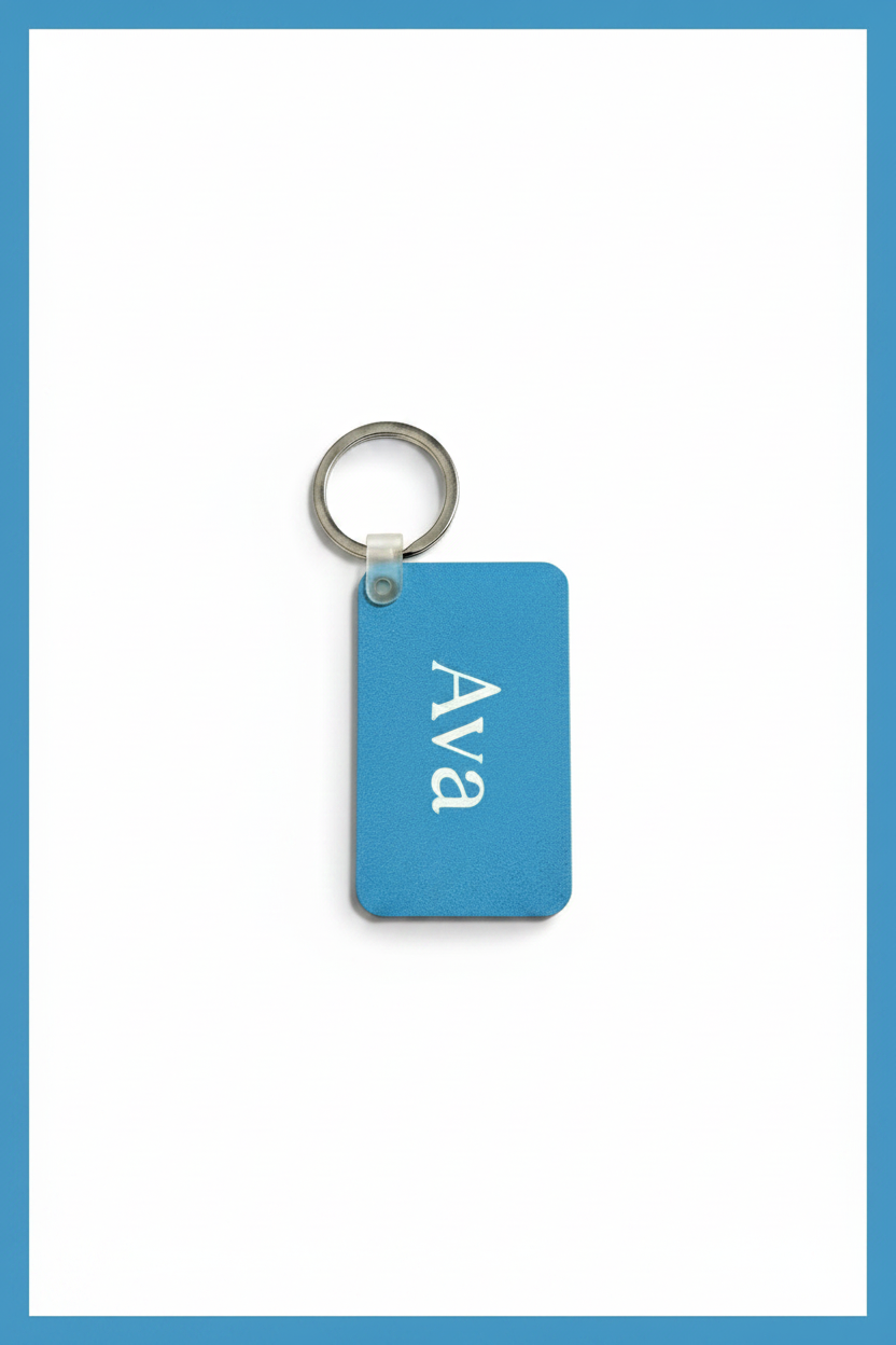 A rectangular blue keychain tag with rounded corners, featuring the name 'Ava' printed vertically in white, attached to a silver metal key ring, set against a white background with a blue border.