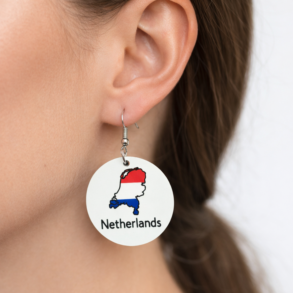 Close-up of a woman’s ear wearing a round earring with the Netherlands map colored in red, white, and blue and the word “Netherlands” printed below.