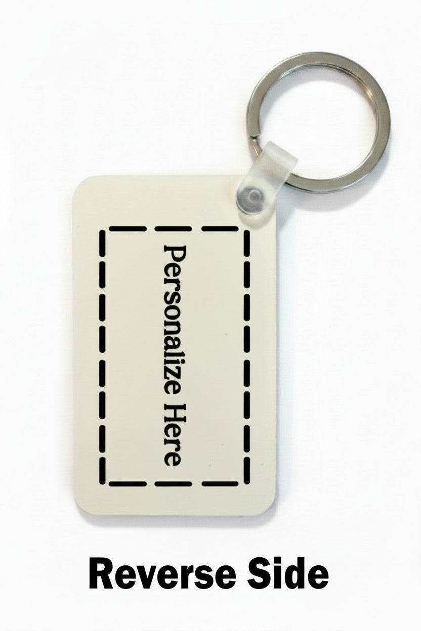 A rectangular personalized key tag shown on a white background, with a metal key ring attached at the top and the text 'Reverse Side' printed below. The tag has a light beige/cream face with black dashed border lines and the words 'Personalize Here' in black vertical text. Roxzell